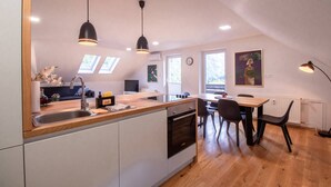 Une cuisine moderne dotée d’un îlot central, de luminaires suspendus et d’un coin repas avec une table et des chaises.
