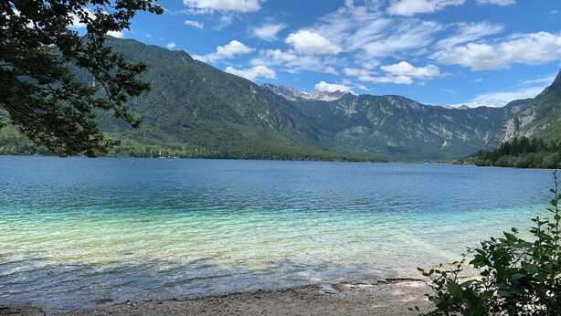Un lac aux eaux cristallines, entouré de montagnes et d’arbres.
