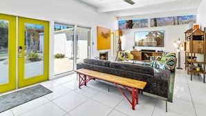 A bright living room with a sofa, a bench, a fireplace, and a TV.