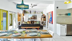 Una sala de estar moderna con un sofá, juego de mesa y una cocina con lavavajillas.