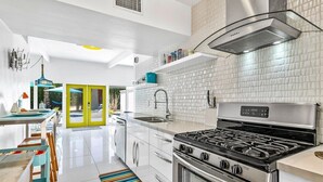 A modern kitchen with a gas stove, stainless steel appliances, and a bright, tiled backsplash.