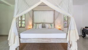 A bed with a canopy, two bedside lamps, and decorative pillows. - Hibiscus (Diani Beach)