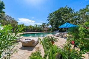 A pool area with lounge chairs and a blue umbrella. - Hibiscus (Diani Beach)