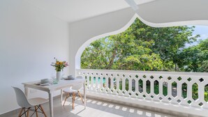 A balcony with a white railing, a dining table with chairs, and a vase with flowers. - Hibiscus (Diani Beach)