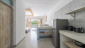 A modern kitchen with a built-in refrigerator, a countertop with a coffee maker, and a wooden shelf. - Hibiscus (Diani Beach)