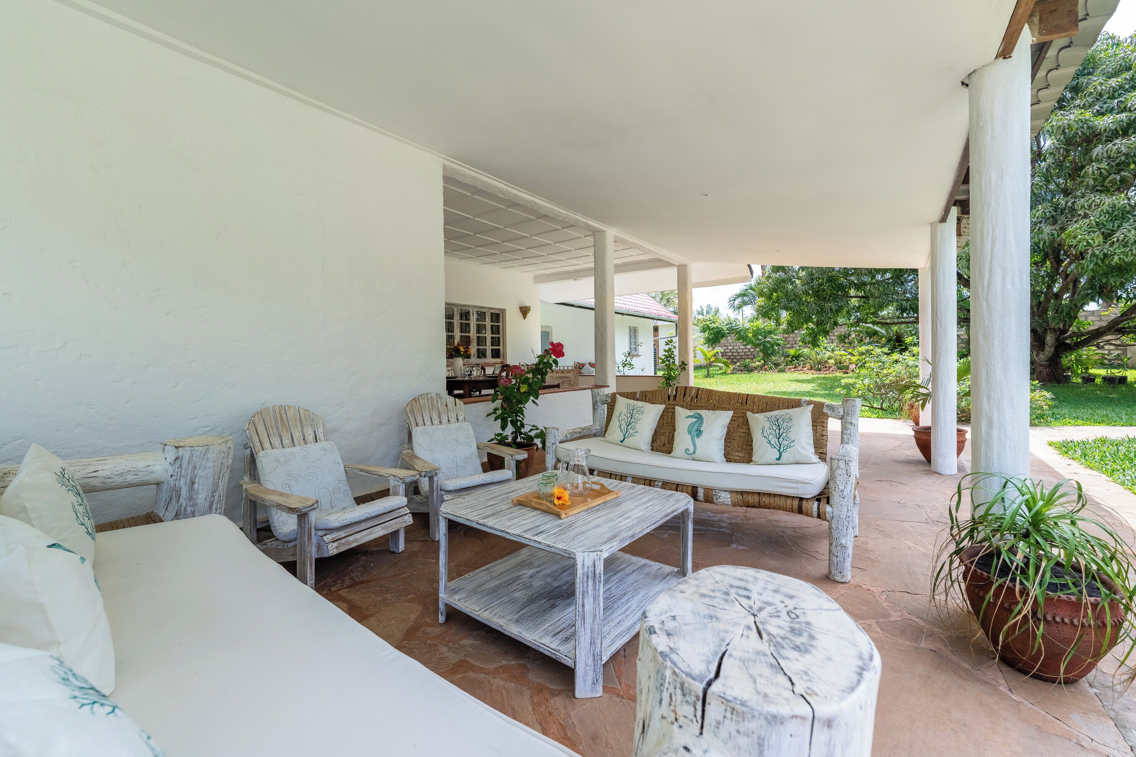 Un espacio al aire libre techado con sofá, sillas y una mesa de centro.