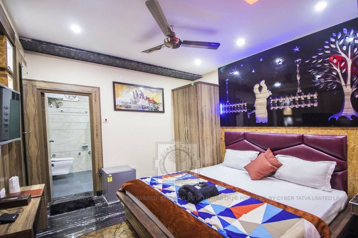 Une chambre d’hôtel équipée d’un lit, d’un ventilateur de plafond, d’une salle de bain avec des toilettes et d’un téléviseur fixé au mur.