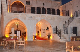 Un edificio histórico con arcos, una escalera y un comedor con mesas y sillas.