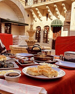 Un área de comedor al aire libre con diversos platos, un tostador PALEX y una fuente de fondo.