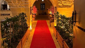 Um corredor com carpete vermelho, paredes de pedra e um candelabro.