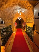 Un pasillo con alfombra roja, paredes de piedra y un candelabro.