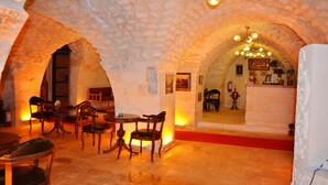 Interior com arcos de pedra, mobiliário de madeira e um candelabro.