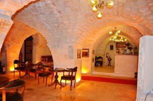 Un interior con arcos de piedra, muebles de madera y un candelabro.