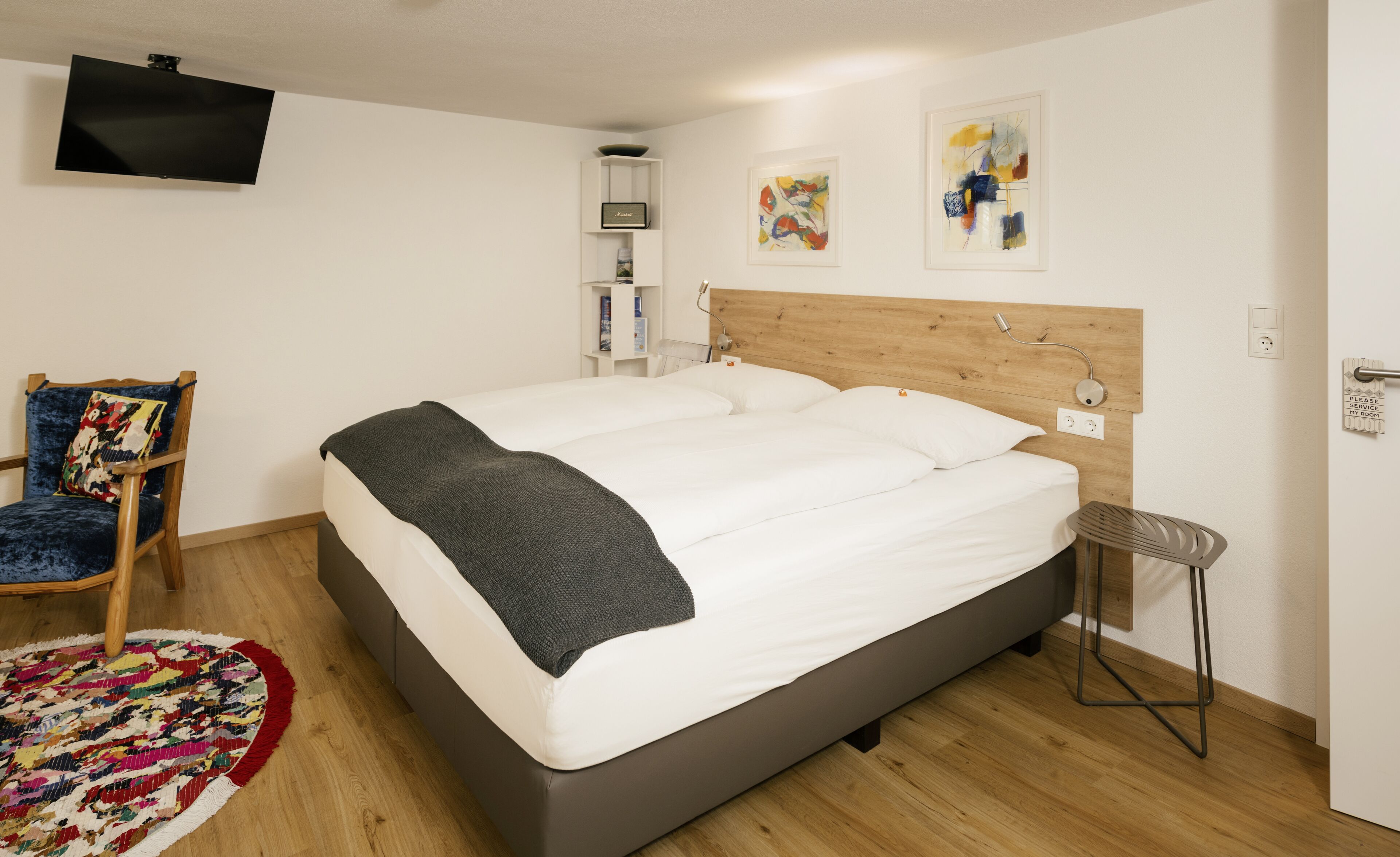 Un dormitorio moderno con una cama grande, un televisor montado en la pared y obras de arte en las paredes.