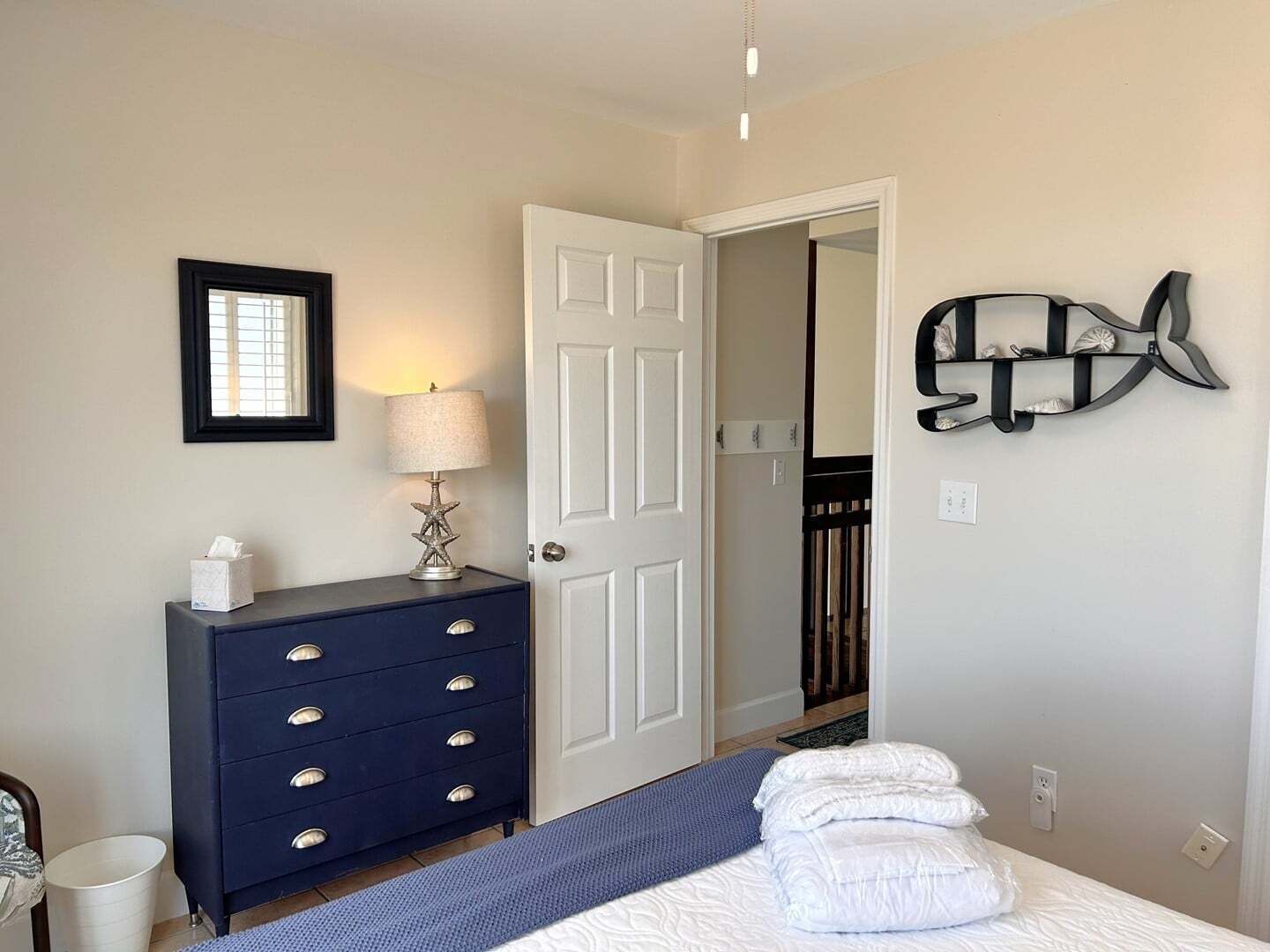 A bedroom with a bed, a dresser, a lamp, a door, and a wall decoration.