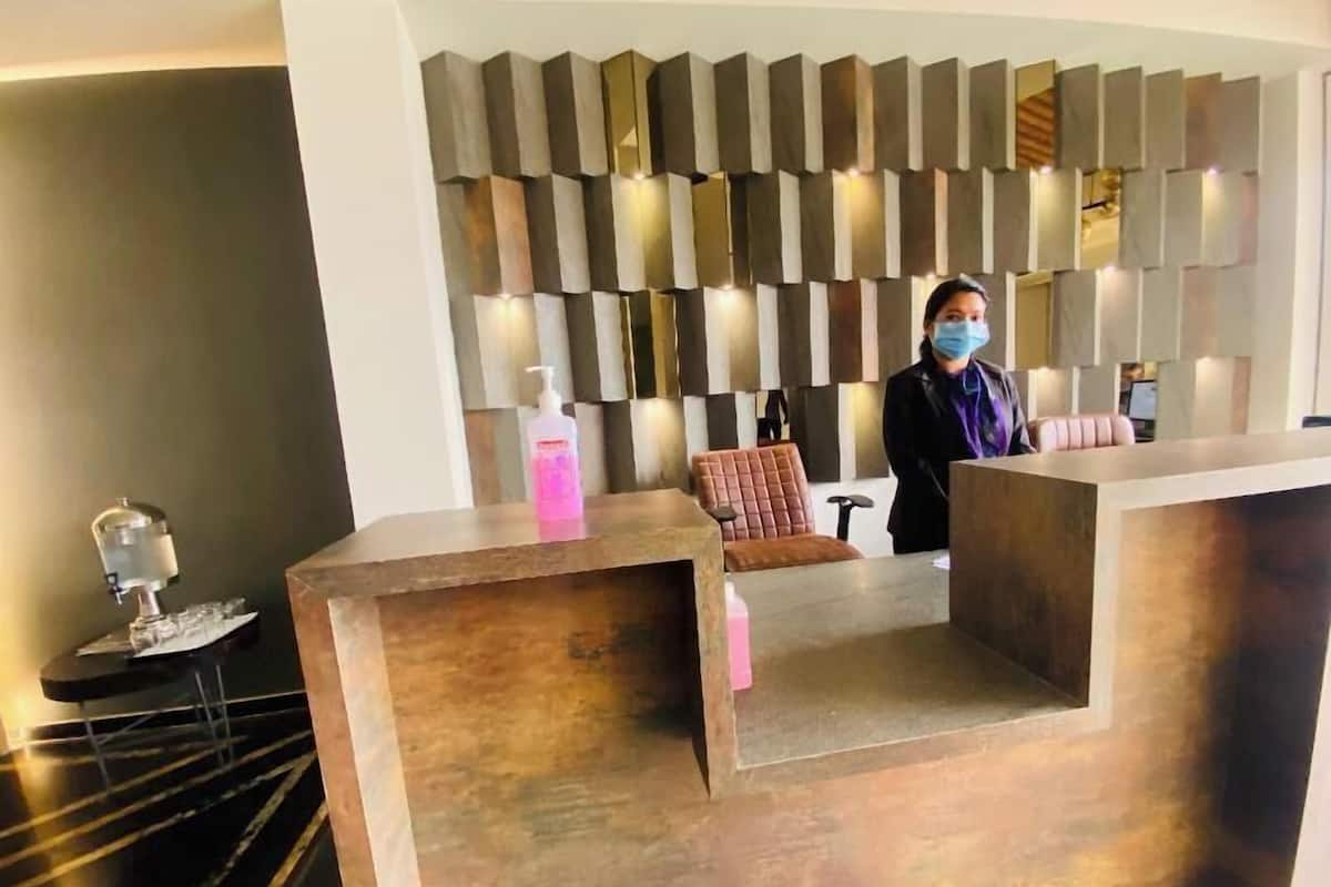 Un área de recepción de diseño moderno, con una mesa de recepción, una zona de estar con un sillón acolchado y una pared decorativa con paneles verticales.