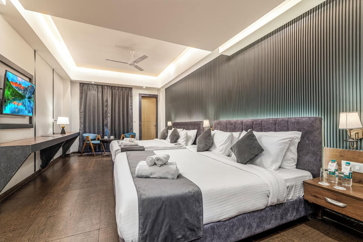 Una habitación de hotel moderna con una cama grande, mesitas de noche, un escritorio y un televisor.