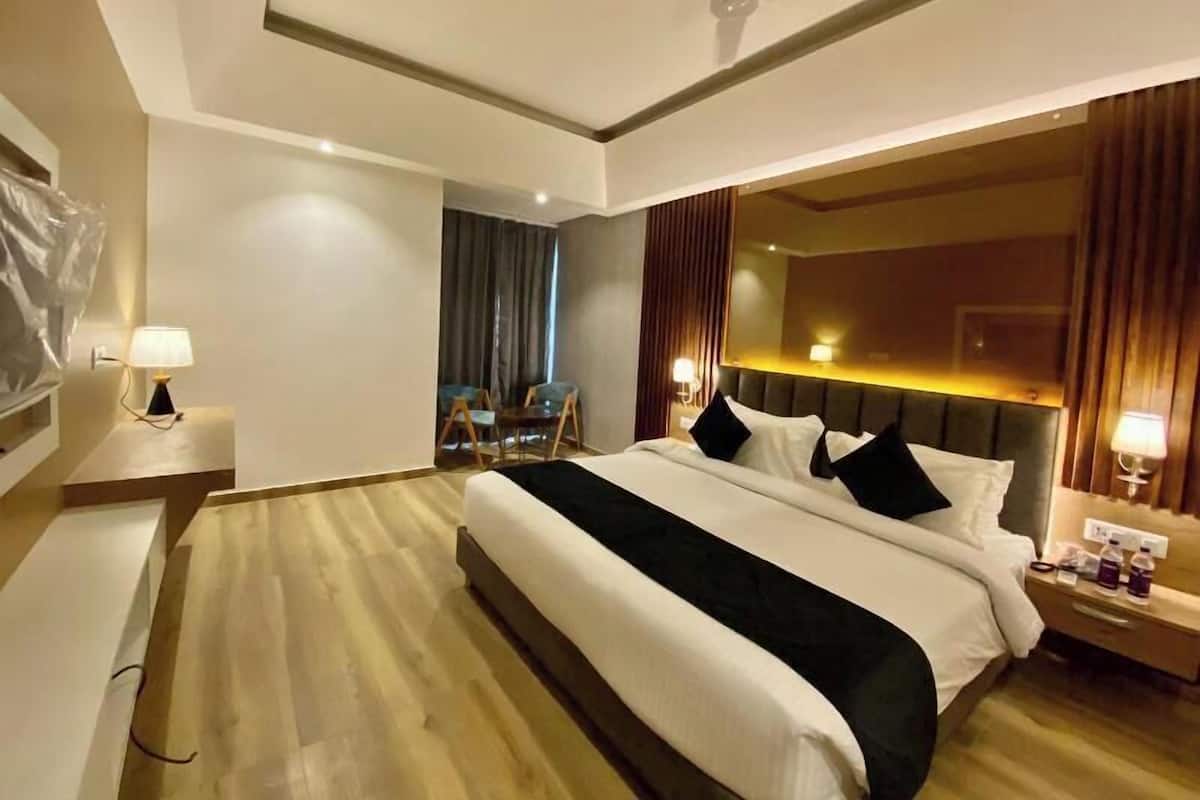 Una habitación de hotel con una cama grande, un ventilador de techo, un escritorio con lámpara y una silla.