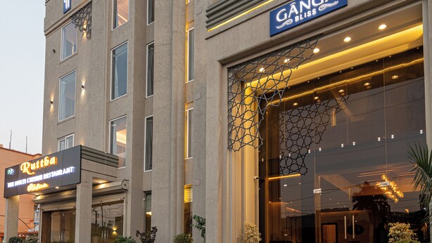 Een hotel met een moderne gevel, waarop de naam 'Ganga Bliss' duidelijk staat aangegeven.