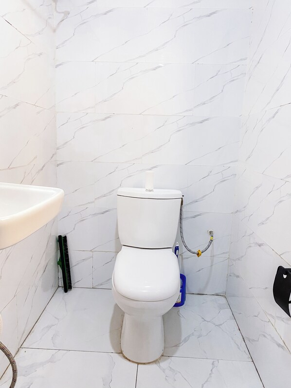 A bathroom with a toilet, a sink, and a marble-tiled wall.