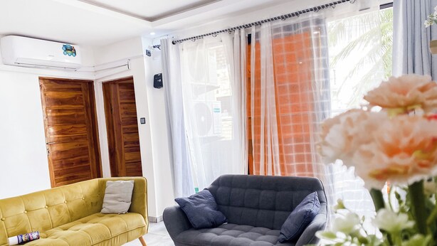 Una sala de estar moderna con un sofá amarillo, un sillón gris y una mesa de centro blanca.