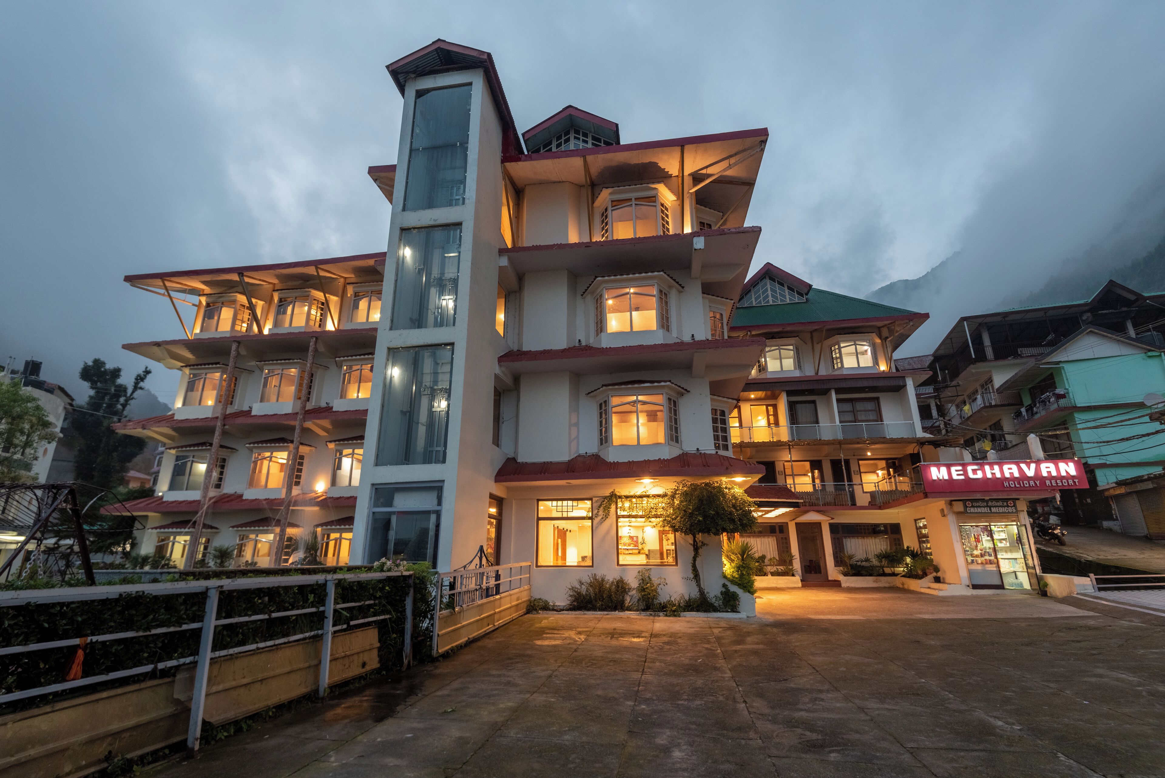 A multi-story hotel with a prominent tower, balconies, and a ground-level shop.