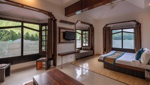 A modern bedroom with a large bed, a TV, and a bench. - Meghavan Resort By DLS Hotels (Dharamshala)