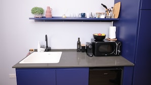A kitchen with a white sink, a microwave, a coffee maker, and a shelf with various kitchen items. - Stylish apartment in central TLV just a short walk from the beach (Tel Aviv)