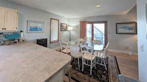 A kitchen with a large island, dining area with chairs, a window with blinds, and a door leading outside. - 5 Bedroom Dog Friendly House with community pool and beach views! (Fenwick Island)