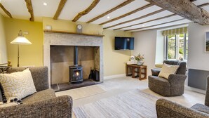 A cozy living room with a fireplace, comfortable seating, a flat-screen TV, and a window with a view. - Joe's Cottage -  Modern, yet cosy, two bedroom cottage - Brigsteer (Brigsteer)