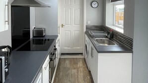 A compact kitchen with a stove, oven, and microwave, a washing machine, and a sink.