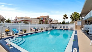 A rectangular pool with a blue edge, surrounded by white lounge chairs and a white fence. - Steps to Beach Access | Updated Condo | Pool | Sleeps 4 (Madeira Beach)