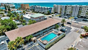 A hotel with a swimming pool, multiple floors, and a view of the ocean. - Steps to Beach Access | Updated Condo | Pool | Sleeps 4 (Madeira Beach)