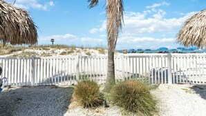 A beach with a white fence, palm trees, and blue umbrellas. - 3 Bedroom 2 Bath Beach View #205 Beach Place Condos (Madeira Beahc)