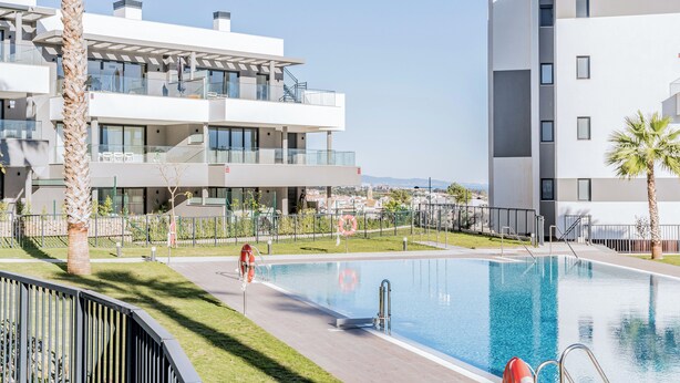 Ein moderner Poolbereich mit freiem Blick auf die umliegenden Gebäude, darunter ein mehrstöckiges Haus mit Balkonen und ein Gebäude mit flachem Dach.