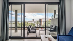 Ein modernes Zimmer mit Balkon, einem blauen Sofa, einem Holztisch und einer Glastrennwand.