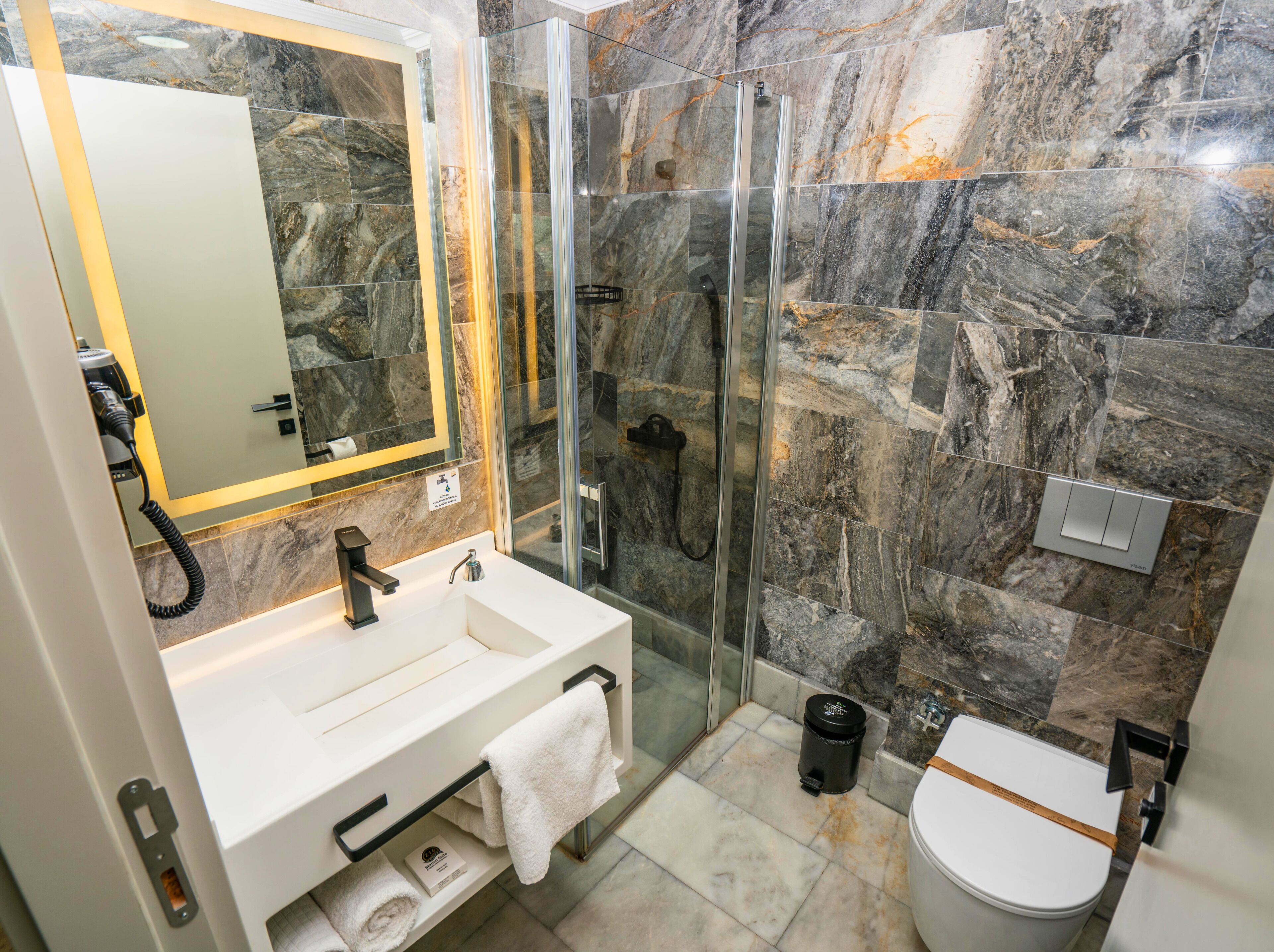 Une salle de bain moderne avec une douche à parois de verre, un lavabo blanc et des toilettes.