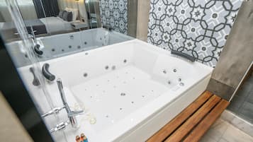 A modern bathroom with a large white bathtub, a glass-enclosed shower area, and a patterned tile wall.