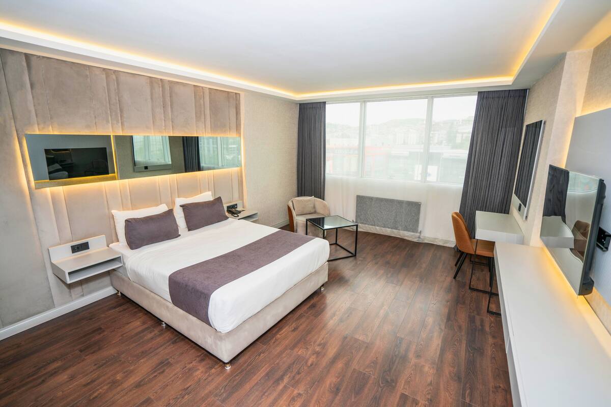 Ein modernes Hotelzimmer mit einem großen Bett, Nachttischen, einem Schreibtisch und einem Sessel.