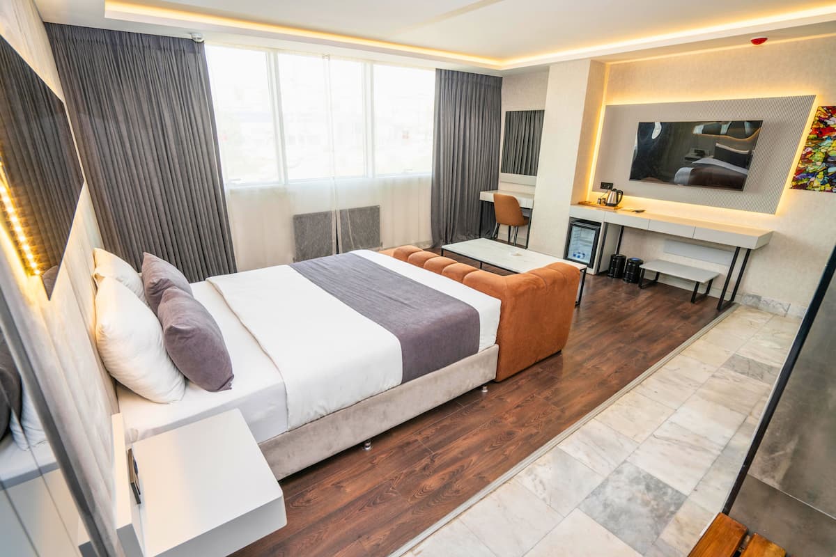 Ein modernes Hotelzimmer mit einem großen Bett, einem Schreibtisch, einem Fernseher und einer Sitzecke.