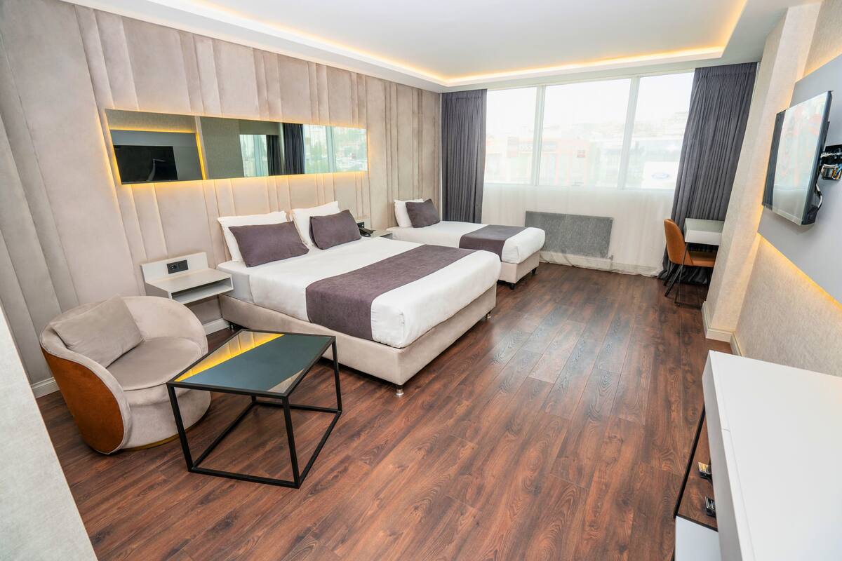 Ein modernes Hotelzimmer mit einem großen Bett, einer Couch, einem Schreibtisch und einem Fernseher.