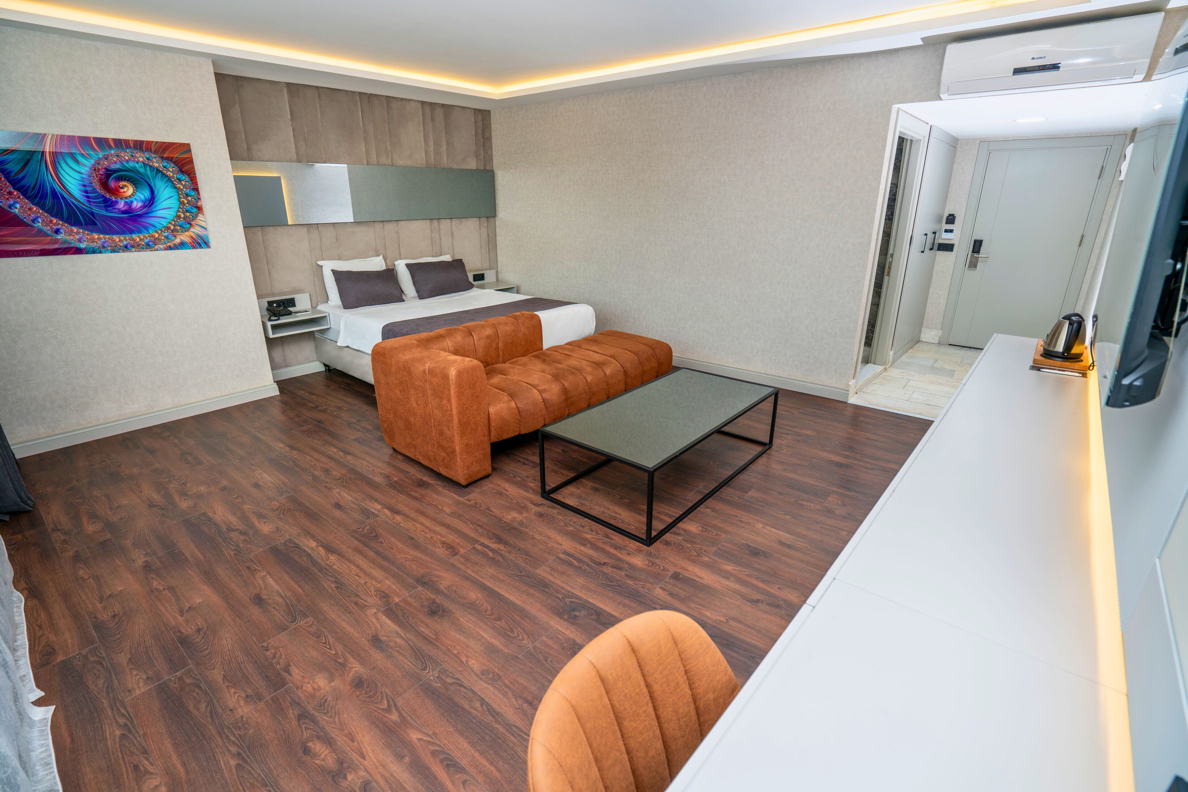 A modern hotel room with a bed, sofa, and desk area.