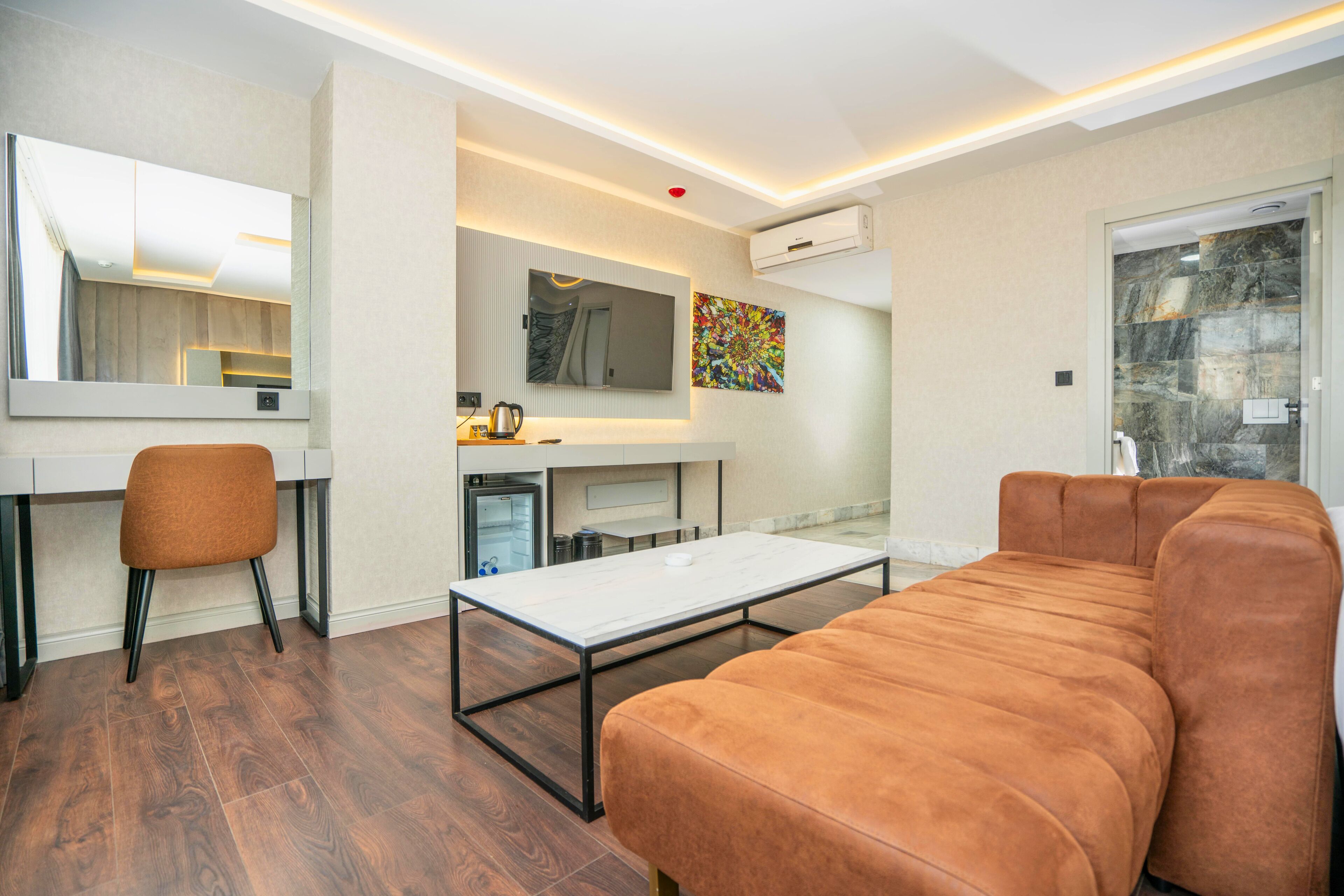 Una sala de estar moderna con sofá, mesa de centro, televisor y área de cocina con microondas y hervidor.