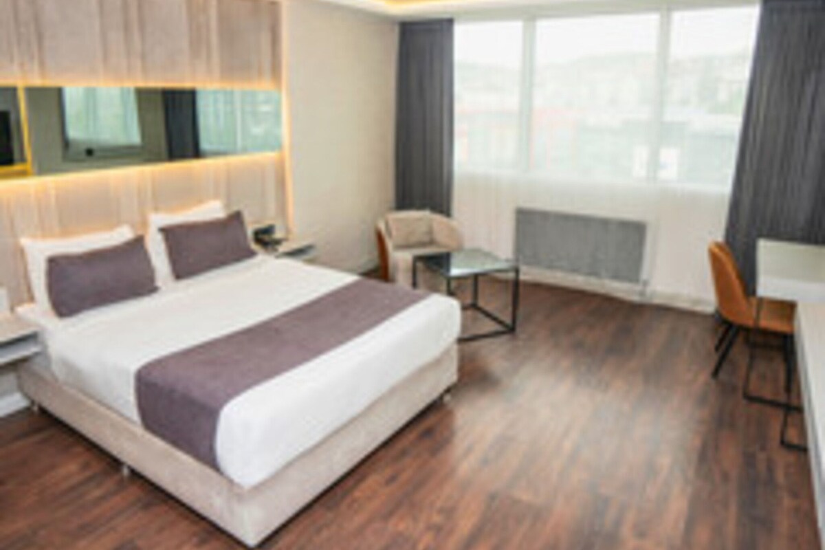 Habitación de hotel moderna con una cama grande, un escritorio y una silla.