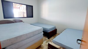 Ein Zimmer mit einem Bett, einem kleinen Tisch und einem Fenster mit Blick auf Gebäude.