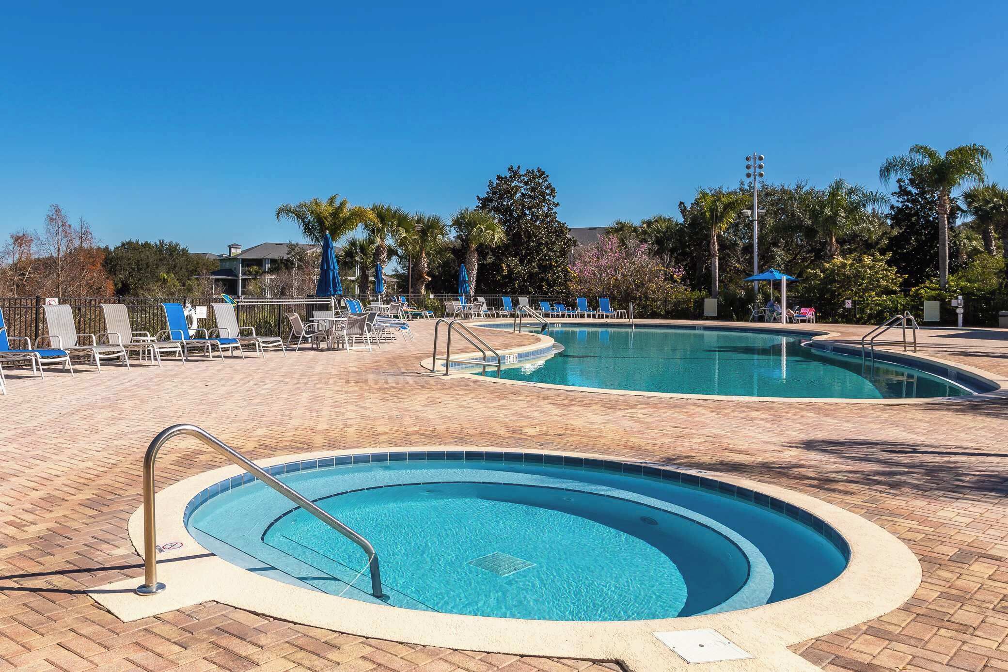 Ein Poolbereich mit zwei runden Pools, Liegestühlen und Palmen.