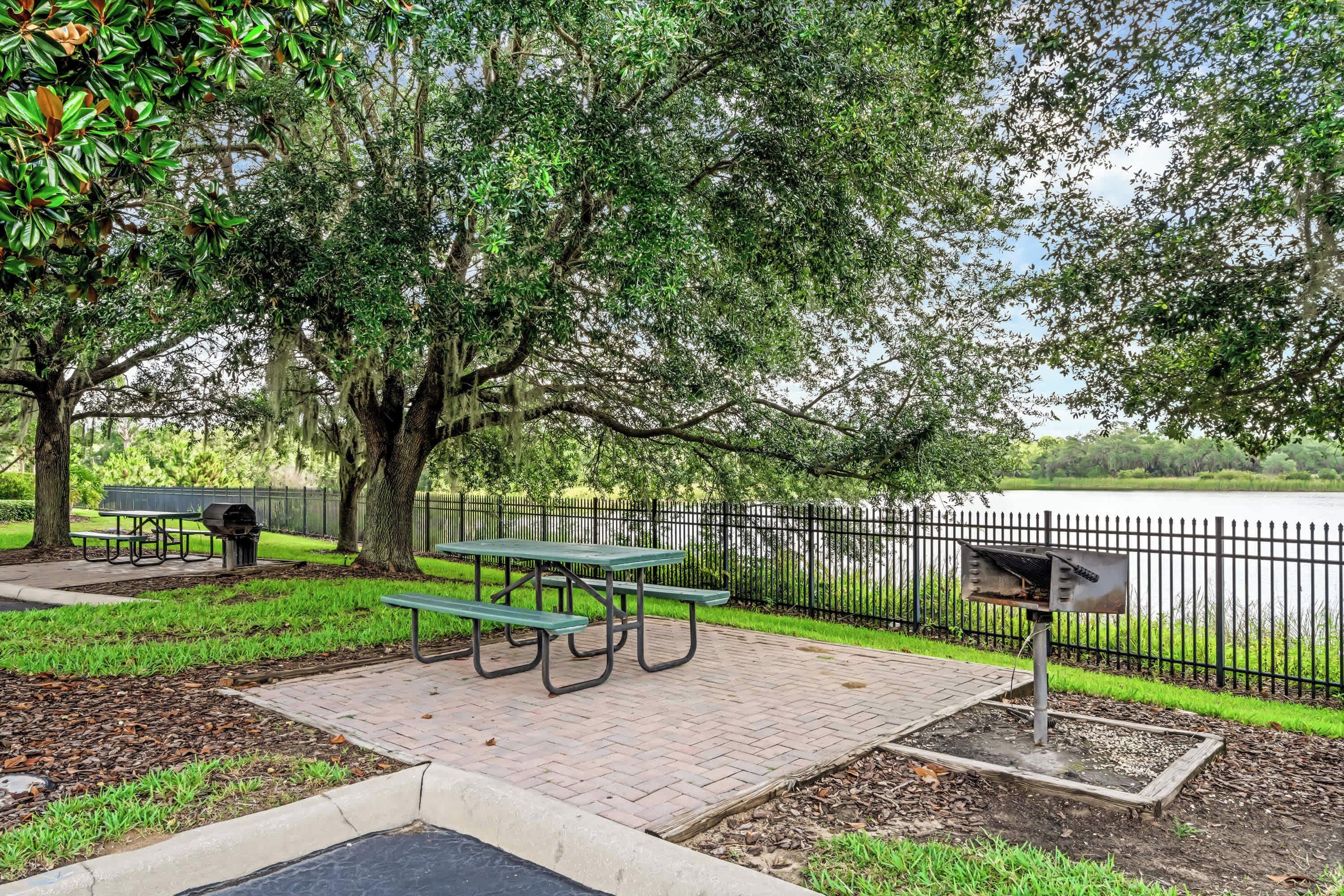A park with picnic tables, a grill, and a mailbox.
