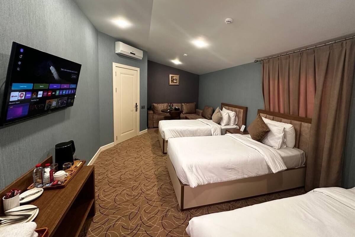 A hotel room with two beds, a TV mounted on the wall, a coffee maker, and a small table with breakfast items.
