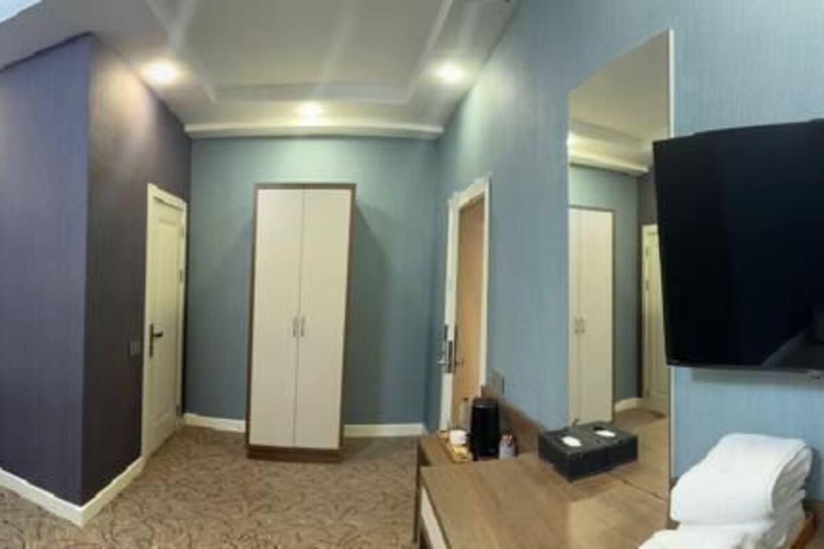 A hotel room with two beds, a desk, a TV, and a wardrobe.