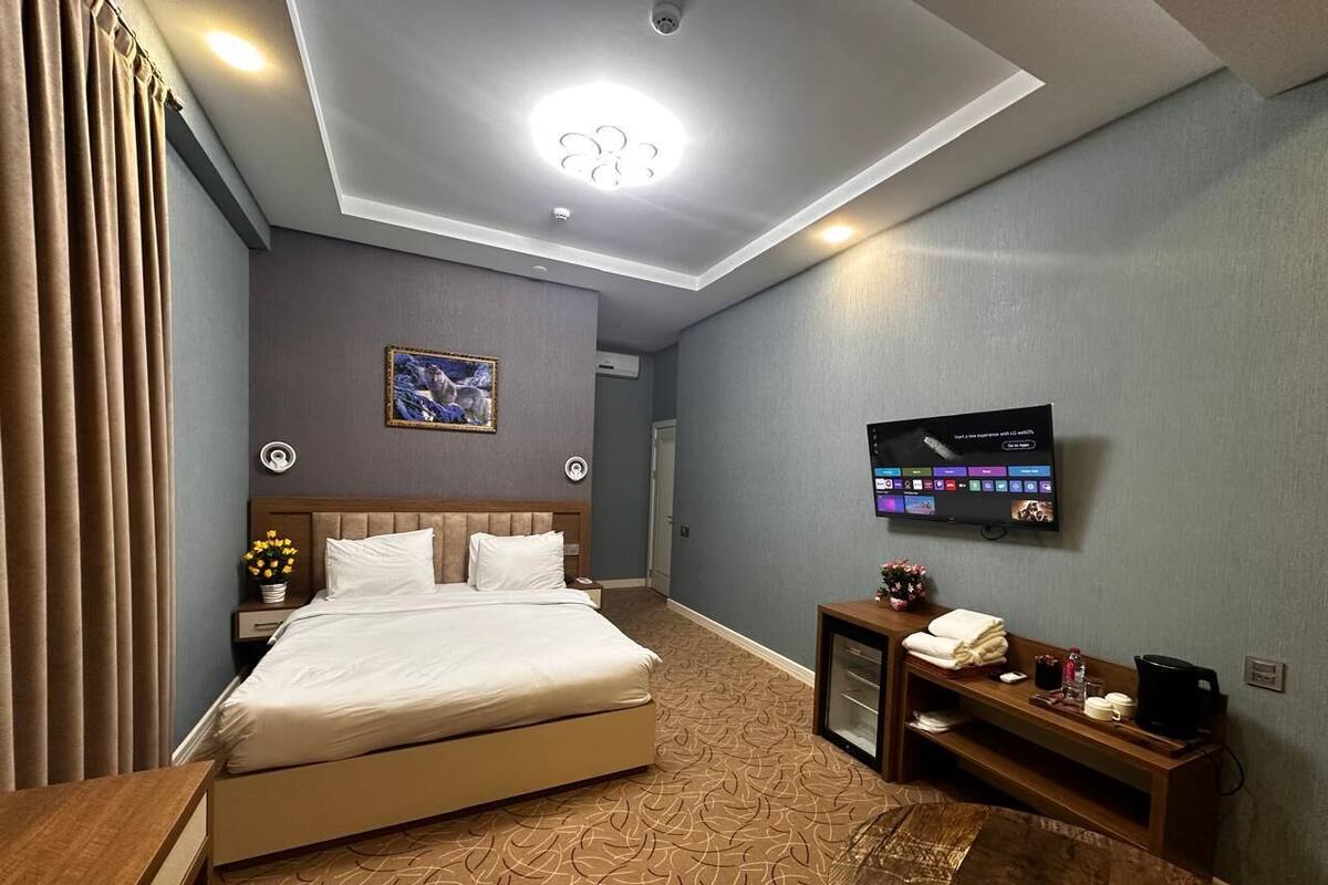 A hotel room with a bed, a TV, a desk, and a small table with a coffee machine.